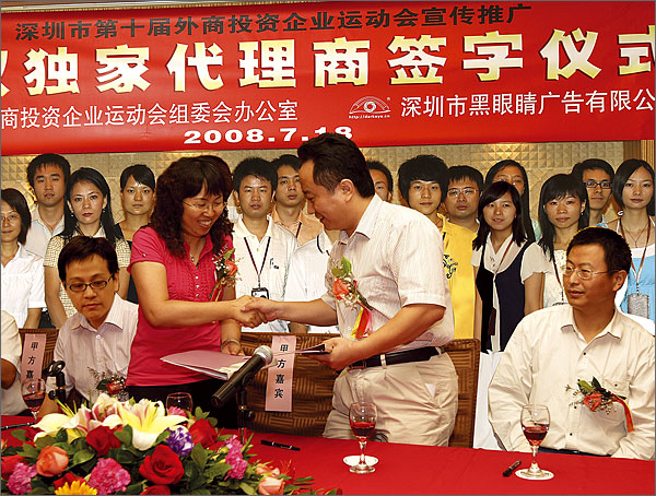 秘書長黃瑛女士和黑眼睛廣告公司藝術總監徐文軍先生交換簽字文件